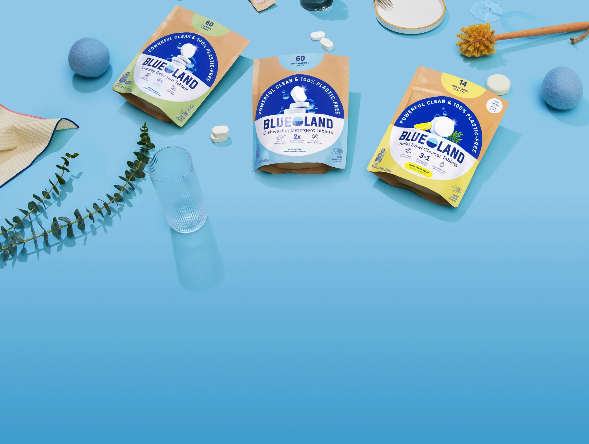 Three packages of BlueLand products on a blue surface with various items around.
