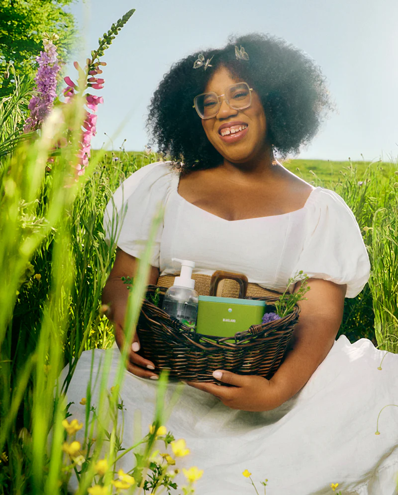 Woman holding a basket with Blueland products in a field of flowers