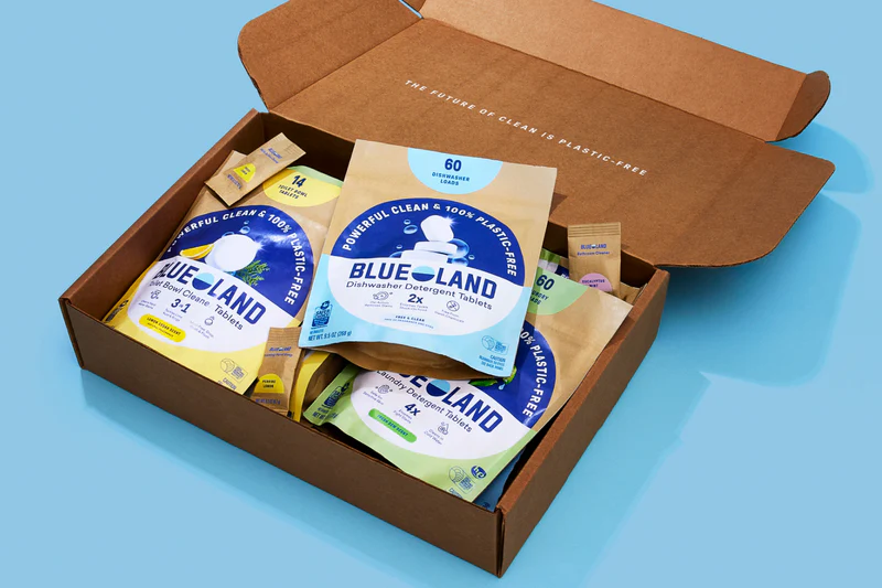 Open cardboard box containing Blue Land product packages on a blue background